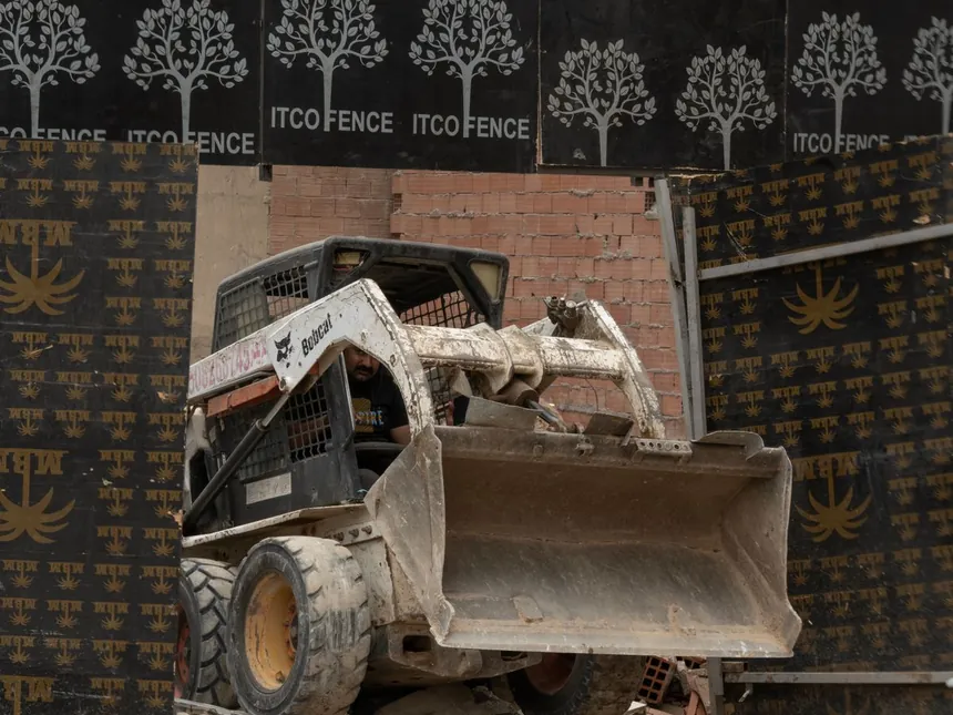 A skid steer clearing broken material from a small demolition site