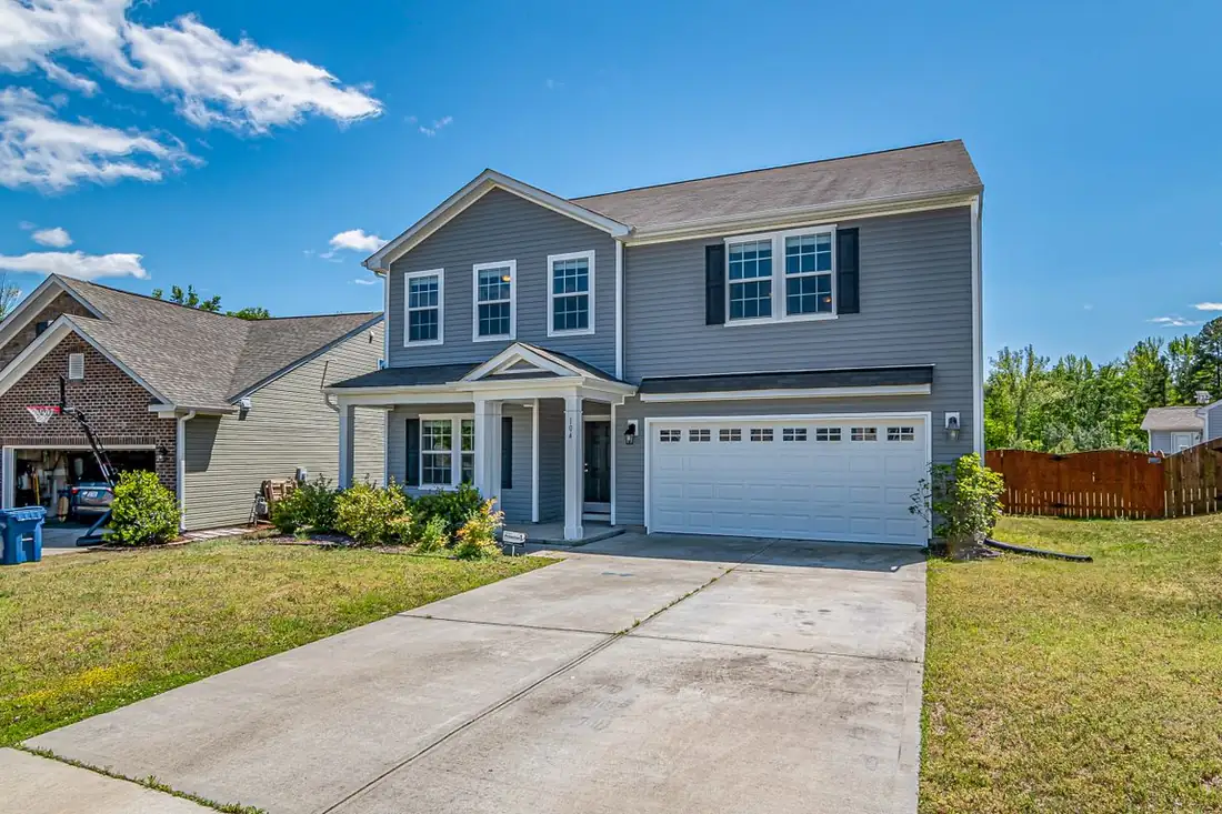 A two-storey suburban home with a clean concrete driveway and front walk