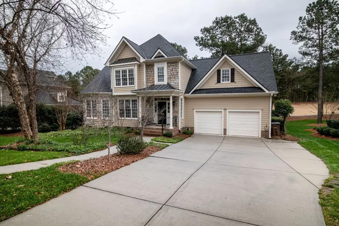 A wide, clean concrete driveway curving up to a two-car garage on a suburban home