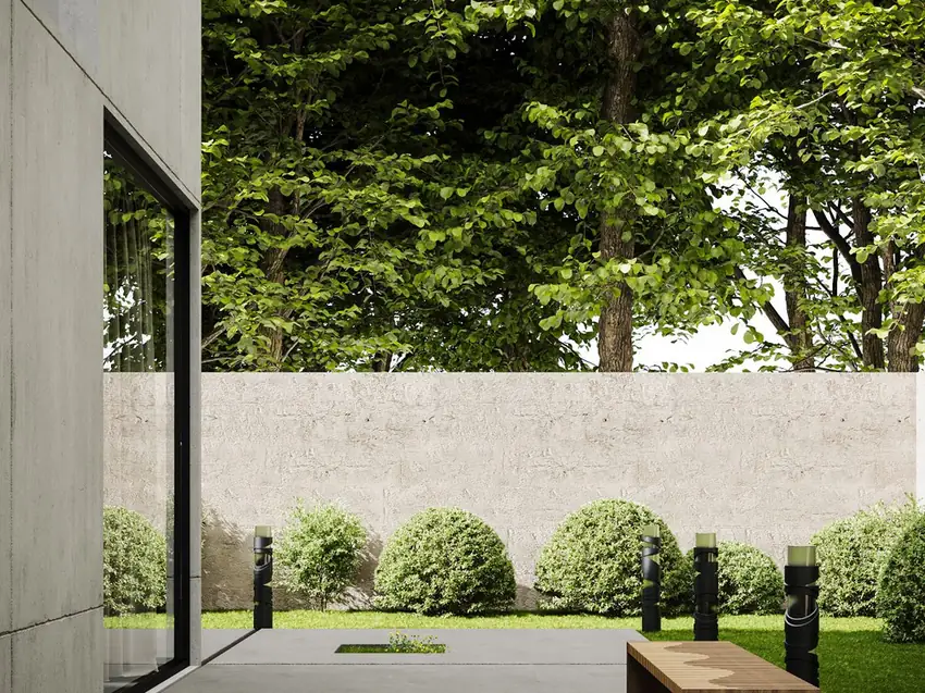 A modern concrete patio with a clean-edged slab, bench seating and a rendered garden wall