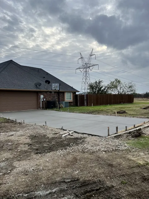 A new concrete driveway poured beside a brick home