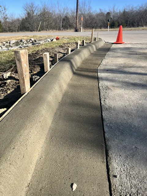 A fresh concrete curb and gutter beside an asphalt road