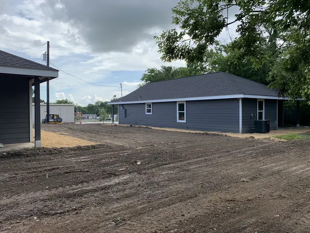 A lot graded and cleared ready for concrete beside a new home