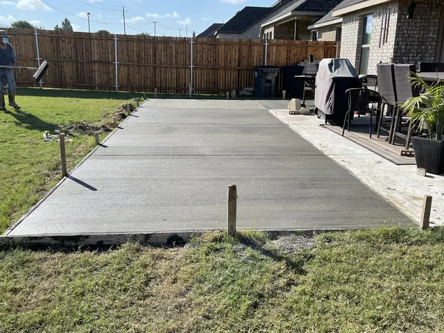 A concrete driveway strip with a paver border running past a patio