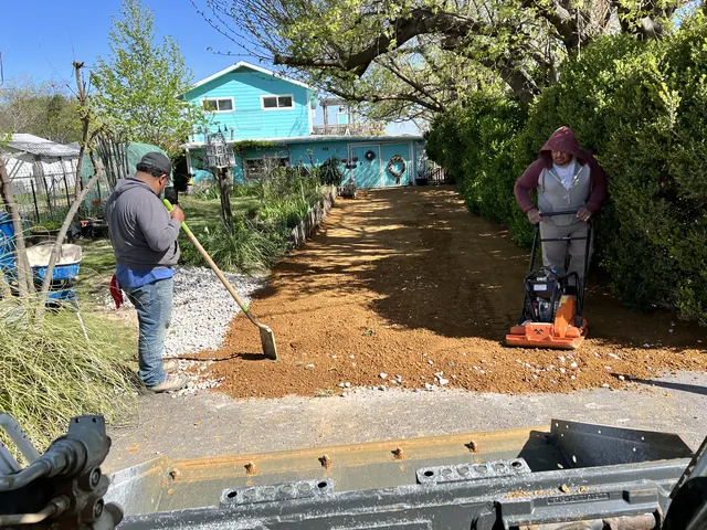 The crew compacting a gravel base for a new walkway