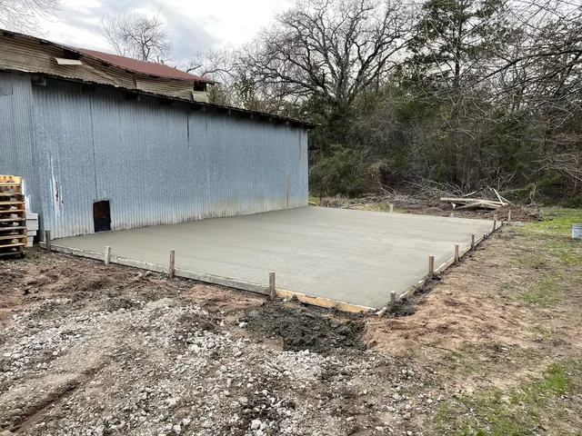 A new concrete slab poured beside a metal building