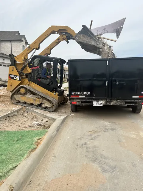 A skid steer loading broken concrete into a dump trailer