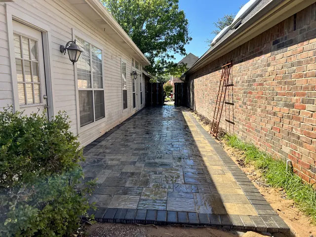 A paver walkway running down the side of a home