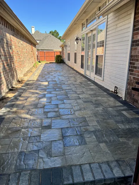 A stamped concrete walkway in a slate pattern between two homes