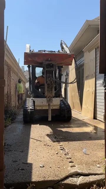 A compact track loader working between two houses