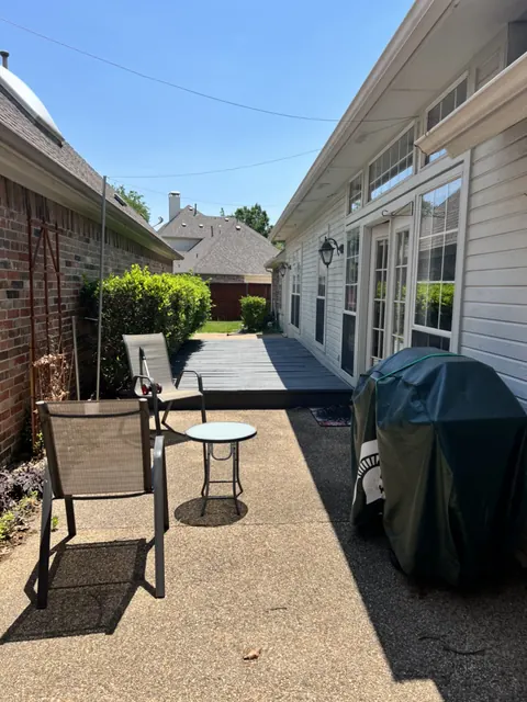 A finished patio and walkway with outdoor furniture beside a home