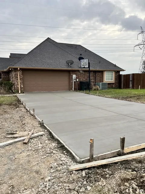 A finished concrete driveway at a brick home with the forms still in place