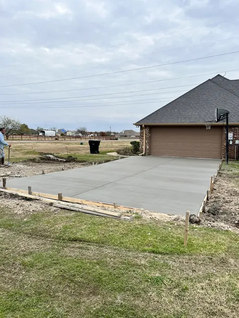 A wide new concrete driveway in front of a brick home