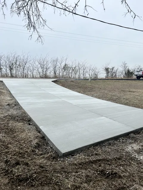 A long concrete driveway running out across a rural property