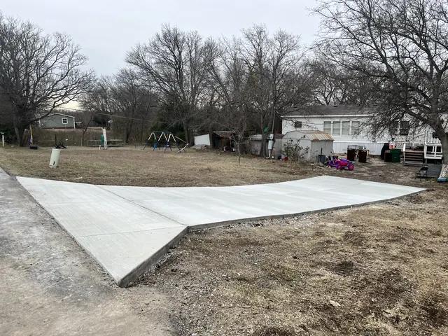 A wide concrete driveway and apron on an open lot