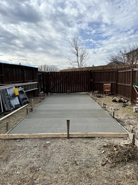 A new concrete patio slab inside a fenced backyard