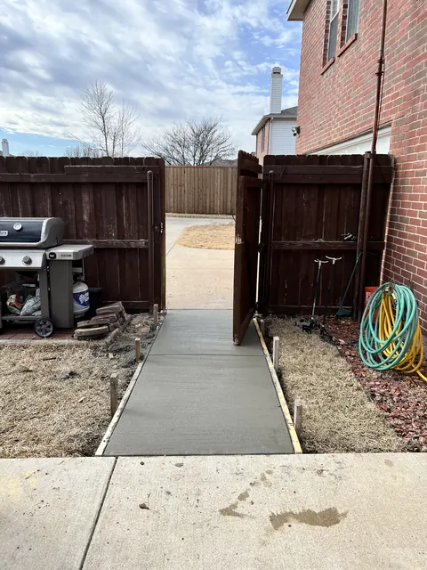 A new concrete sidewalk running from a side gate