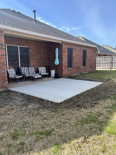 A finished concrete patio off a covered porch at a brick home
