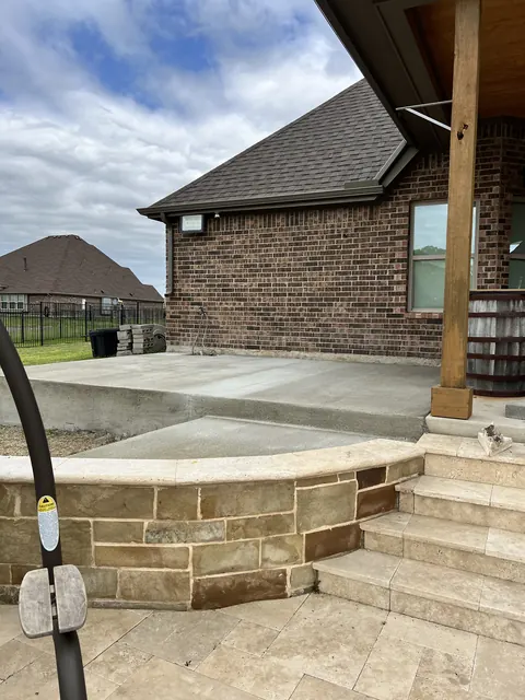A patio with a stone veneer seat wall and stone steps