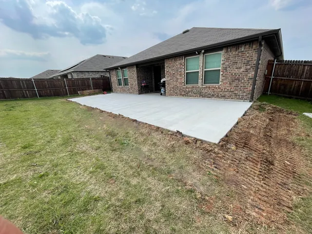 A new concrete patio slab at the rear of a brick home