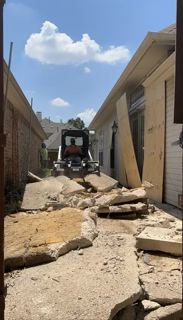 Broken concrete cleared out of a side yard by skid steer
